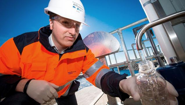 Melbourne Water employee fills a bottle with water at a treatment plant