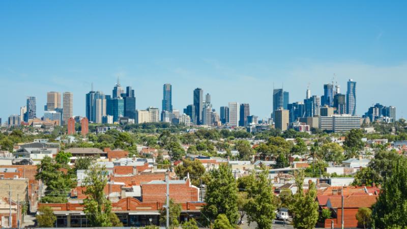 Melbourne city skyline with brick houses and trees in the foreground