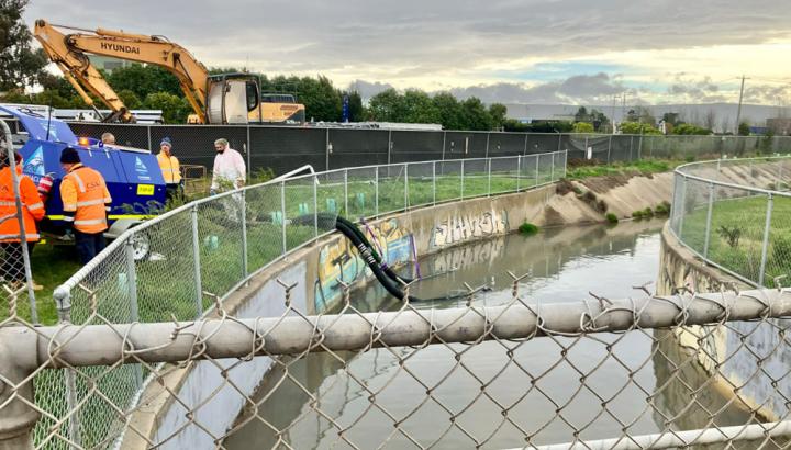 Melbourne Water staff pump water contaminated water from a creek