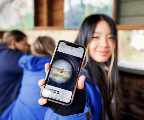 High school student showing the camera a photo she has taken of a bird on her phone