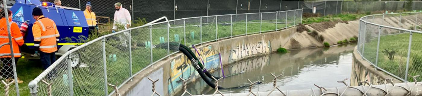 Melbourne Water staff pump water contaminated water from a creek