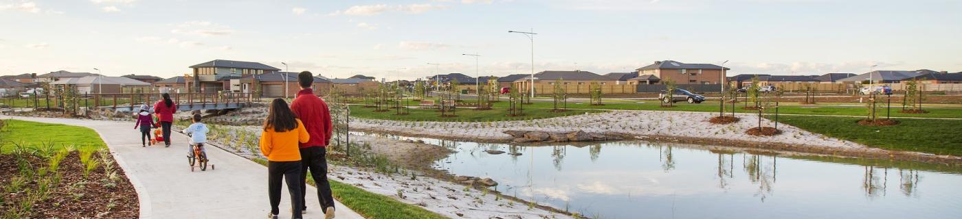 A family walking on a footpath by a retarding basin in Featherbrook Estate in June 2022