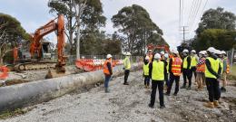 People in hi-vis vests stand in front of pipeline