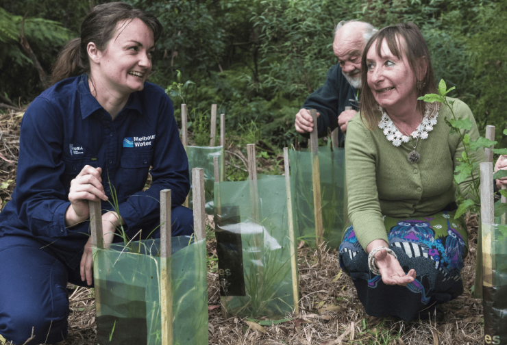 A Melbourne Water employee and a community member planting trees together