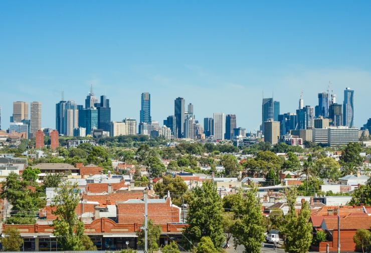 Melbourne city skyline with brick houses and trees in the foreground