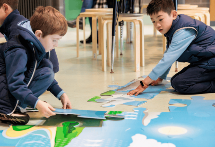 Two primary school children putting together an oversized jigsaw puzzle