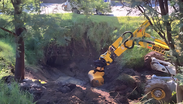 Earth moving equipment clearing out soil from in front of a drain