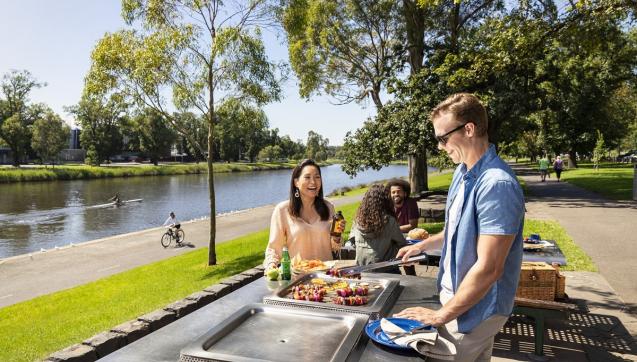 People barbecuing along the Yarra with a cyclist, paddler and walkers in the background