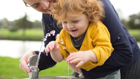 A woman and her child drink from a public water fountain